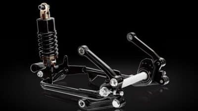 Advanced motorcycle suspension and linkage system against black background, showcasing engineering and design precision.