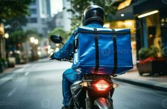 Delivery person on a motorcycle with a blue insulated bag, navigating an urban street for fast online food delivery service.