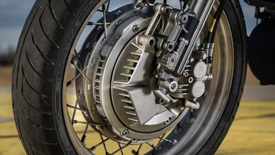 Close-up of a motorcycle wheel with visible disc brake, showcasing intricate metalwork and tire tread details.
