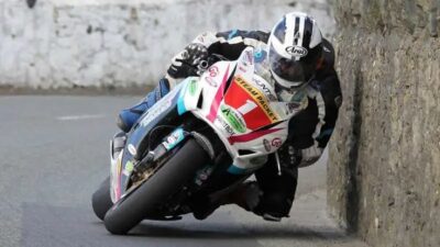 Motorcyclist expertly leans into a sharp turn during a thrilling road race, showcasing skill and precision in high-speed competition.